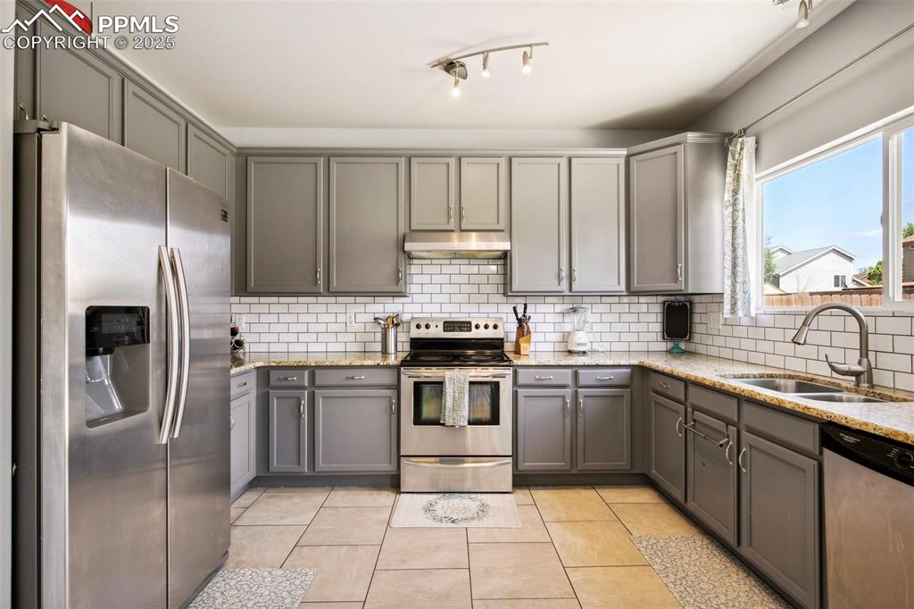 Image 14 of 28: Kitchen featuring appliances with stainless steel finishes, gray cabinetry,