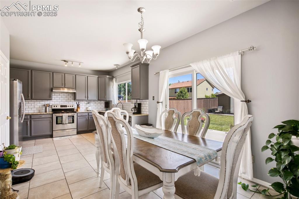 Image 17 of 28: Dining space with a chandelier and light tile patterned floors
