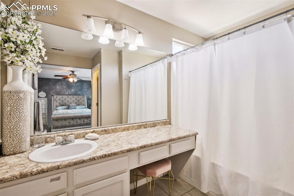 Image 21 of 28: Full bathroom featuring connected bathroom, vanity, ceiling fan, tile patte