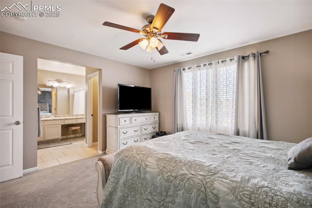 Image 22 of 28: Bedroom with light carpet, light tile patterned flooring, ceiling fan, and 