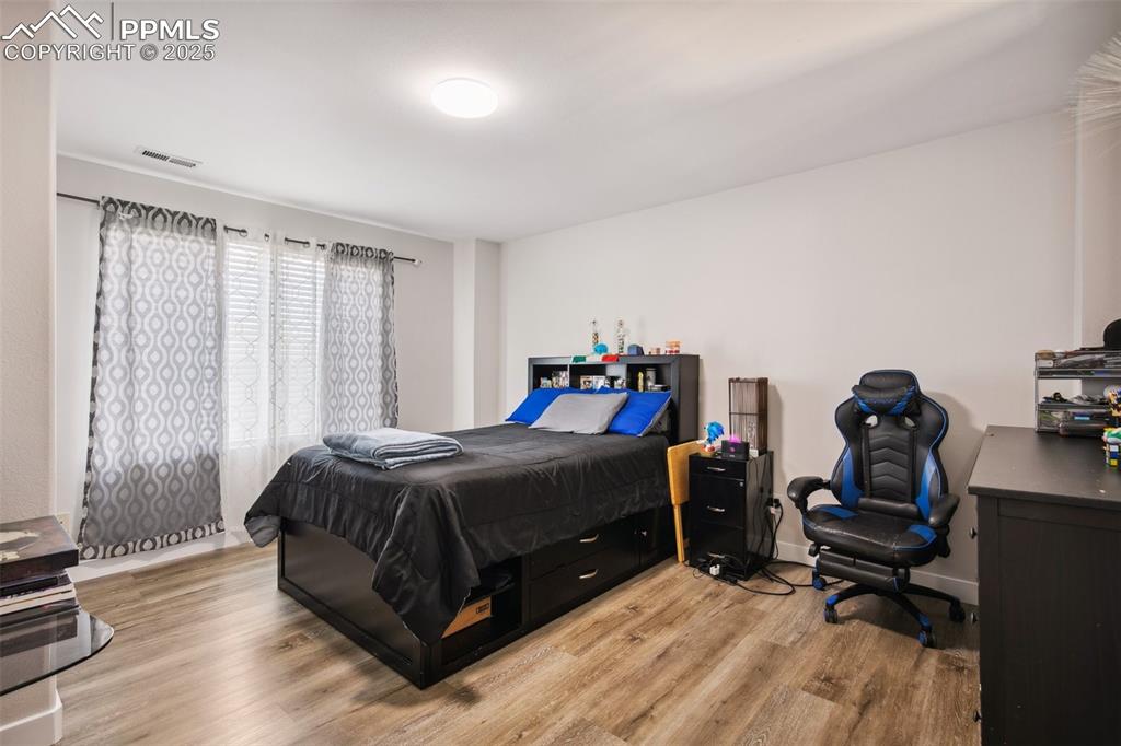 Image 24 of 28: Bedroom with light wood-style floors and a desk