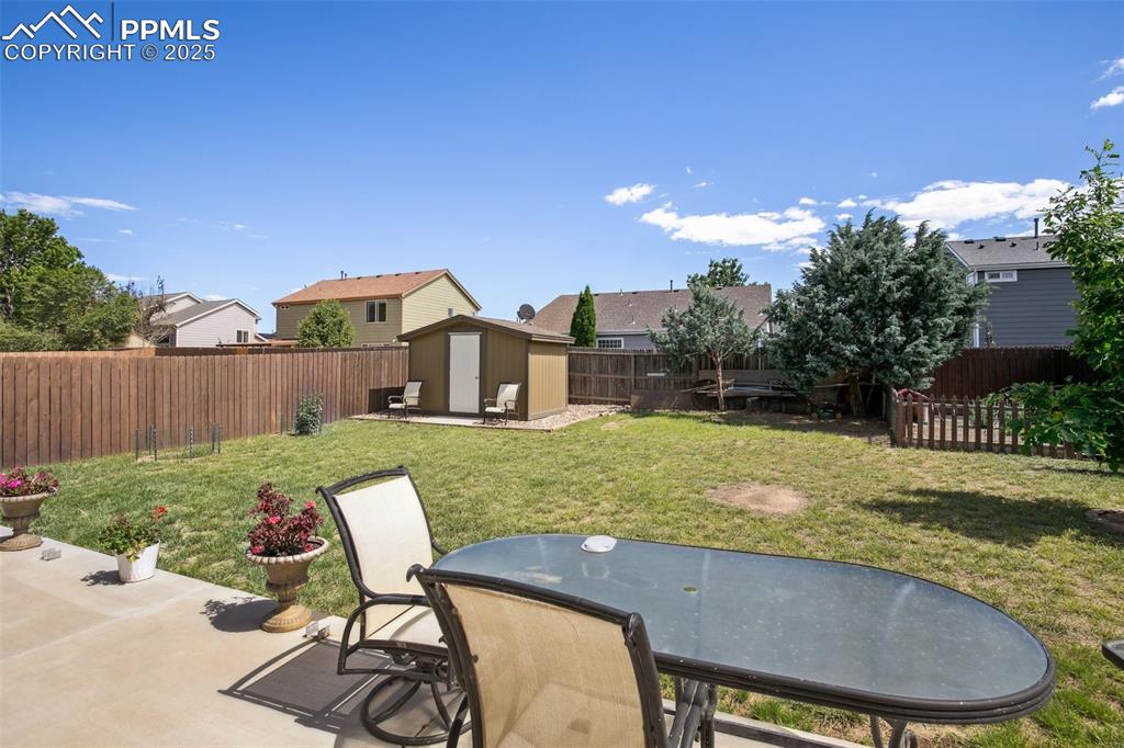 Image 26 of 28: Fenced backyard with a storage unit, a patio area, and outdoor dining area