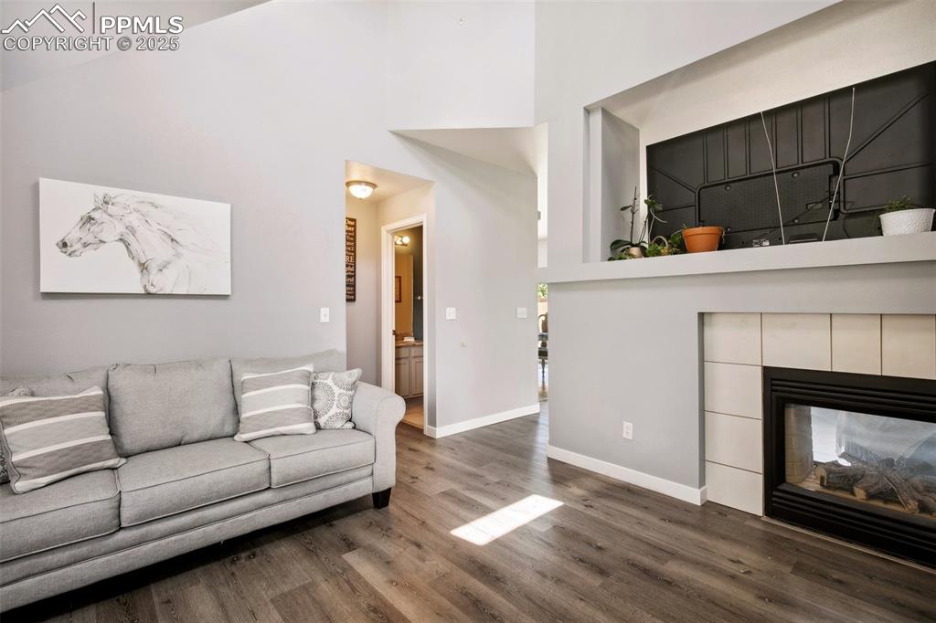 Image 6 of 28: Living room featuring a towering ceiling, wood finished floors, and a tile 