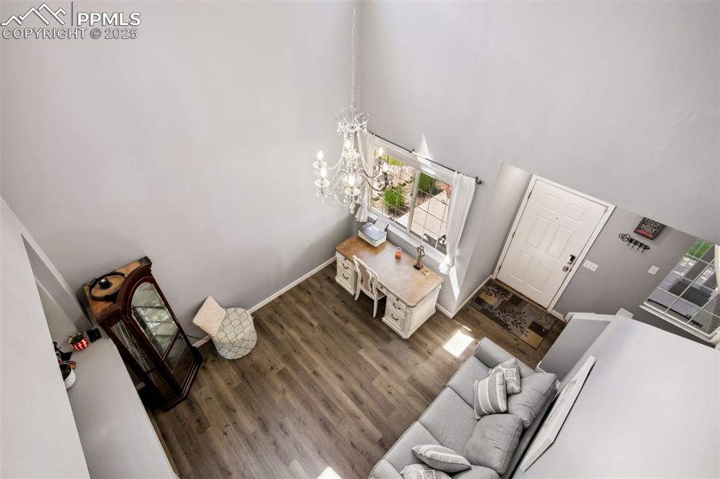 Image 7 of 28: Living area featuring wood finished floors, a chandelier, and a towering ce