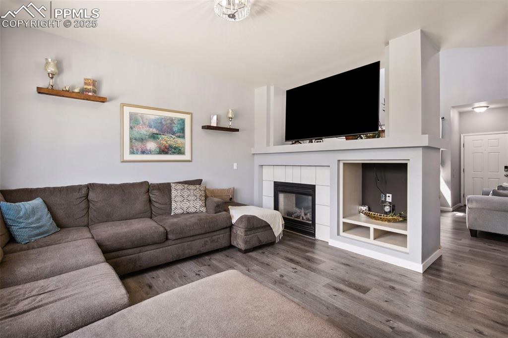 Image 8 of 28: Living room featuring wood finished floors and a tiled fireplace