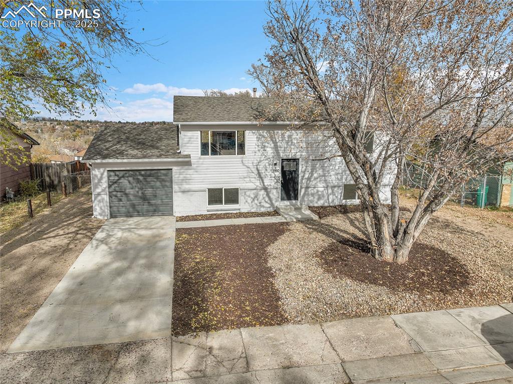 Caption: Split foyer home featuring driveway, a shingled roof, and a garage