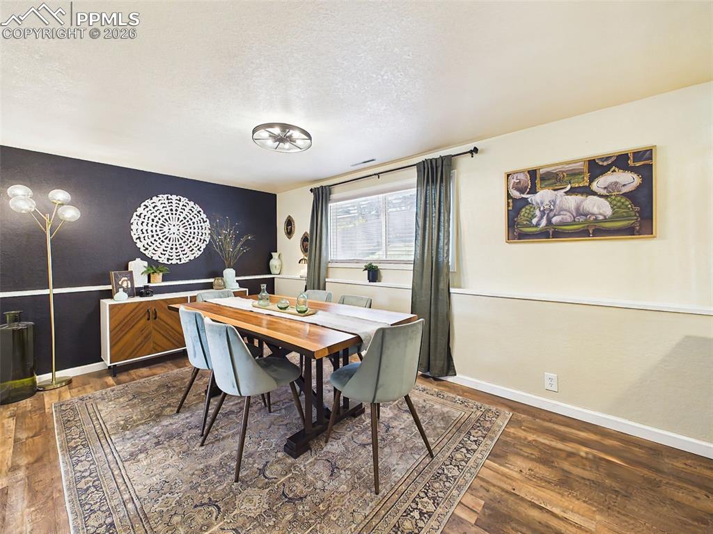 Image 18 of 50: Warm and inviting dining space featuring rich wood flooring, a statement li