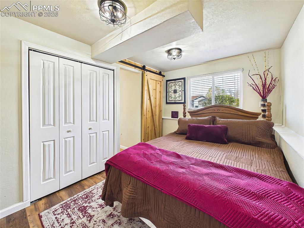Image 23 of 50: Comfortable bedroom with wood-style flooring, neutral tones, and a function