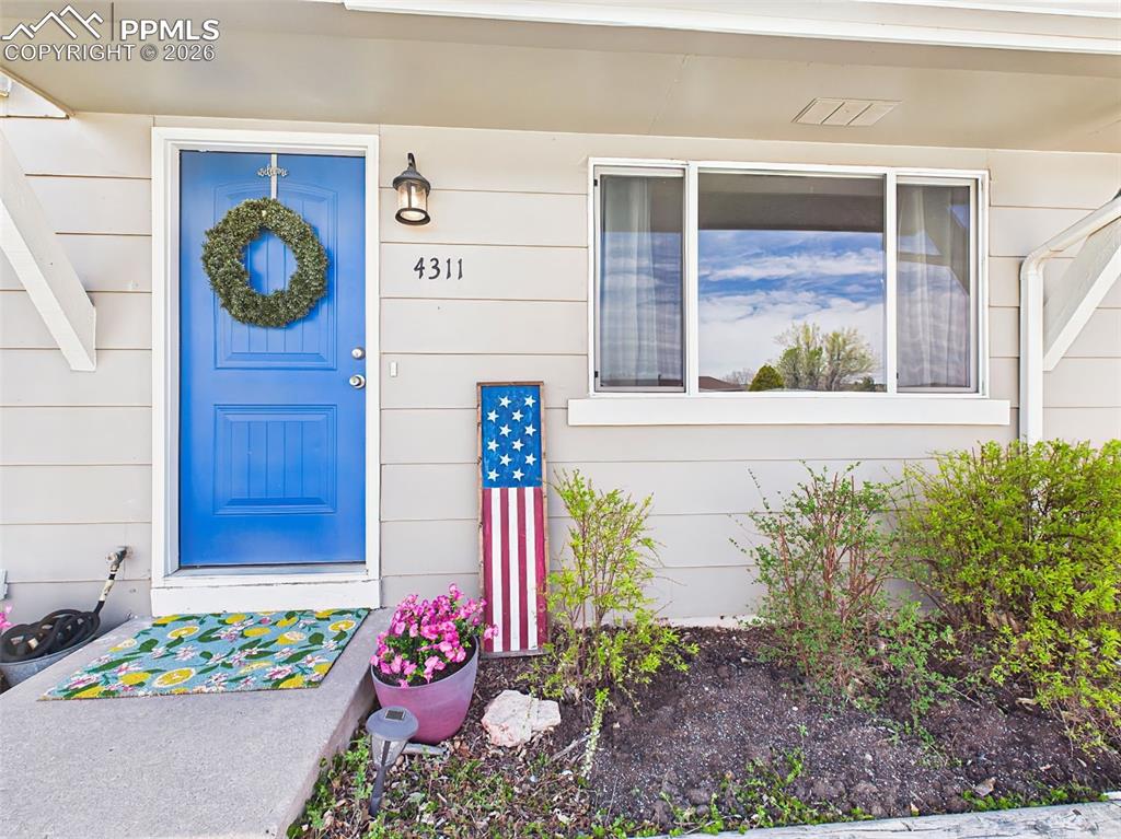 Image 3 of 50: Welcoming front entry with a vibrant blue door, decorative wreath, and char