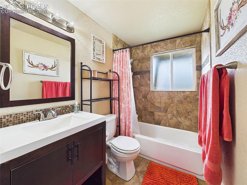 Image 30 of 50: Updated bathroom featuring a modern vanity, tiled tub/shower surround, and 
