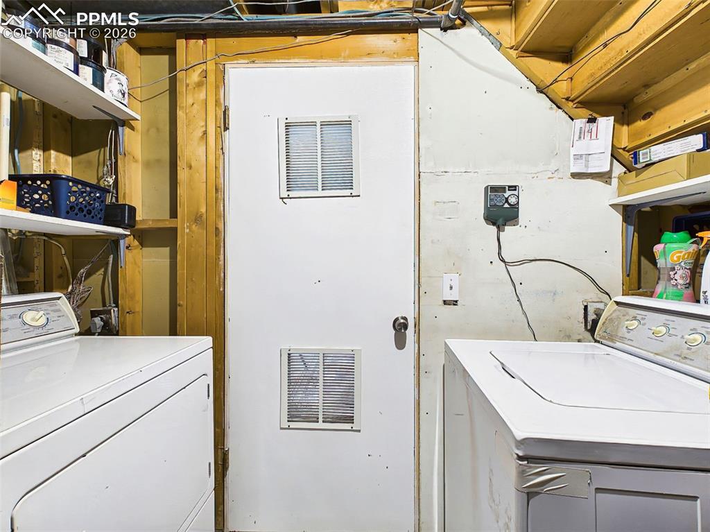 Image 31 of 50: Functional laundry area with washer and dryer, built-in shelving for storag