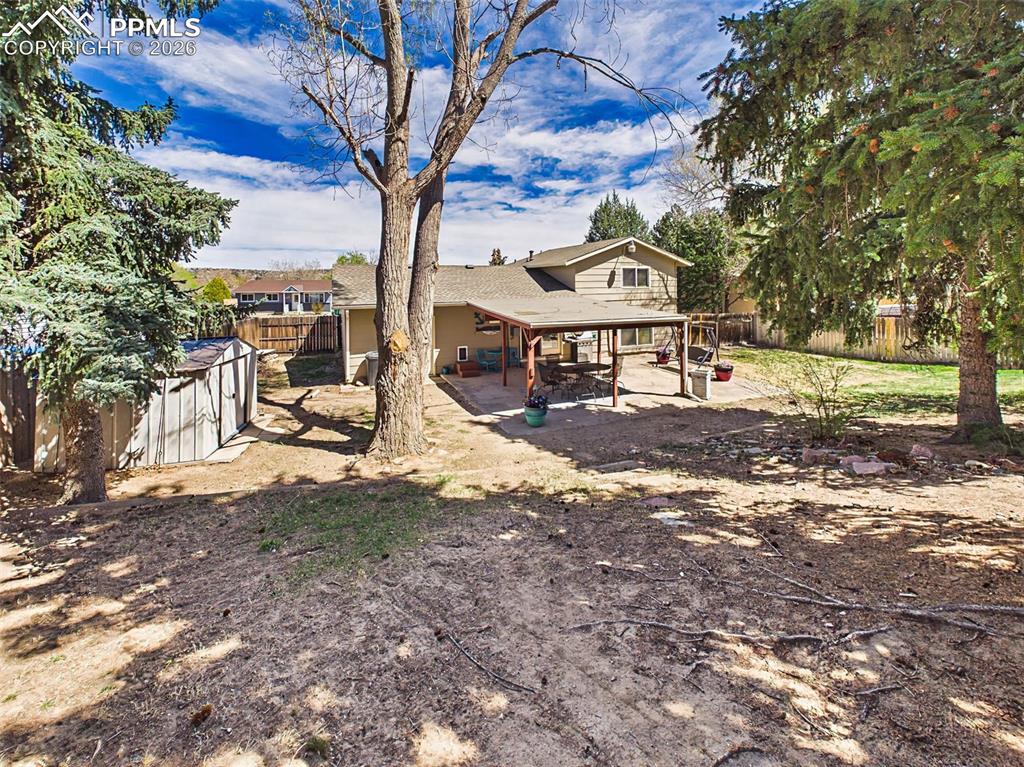Image 34 of 50: Expansive backyard with mature trees and a covered patio, offering a privat