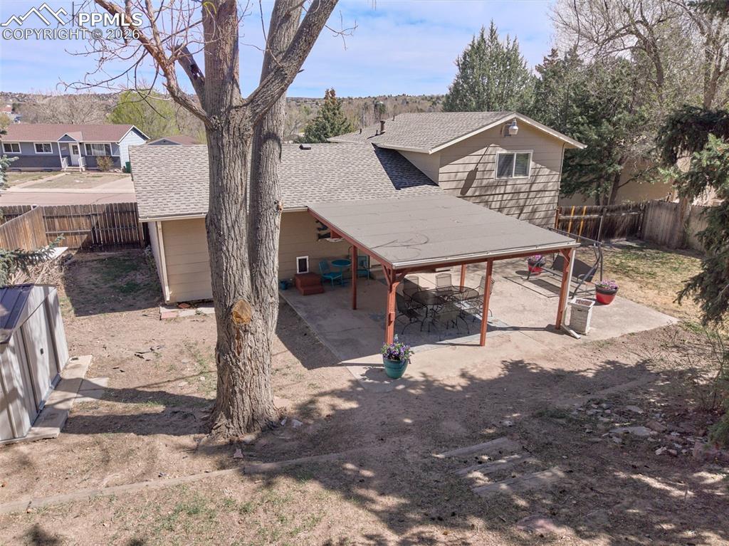 Image 35 of 50: Expansive backyard with mature trees and a covered patio, offering a privat