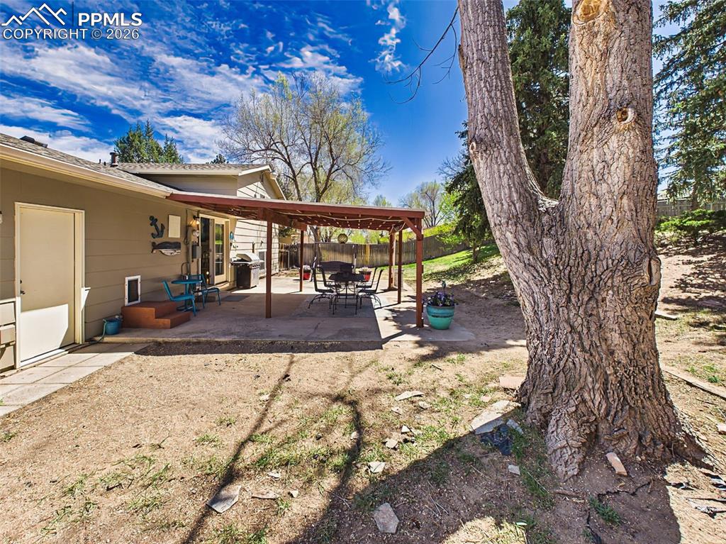 Image 37 of 50: Spacious backyard with mature trees and a fully fenced layout, offering pri