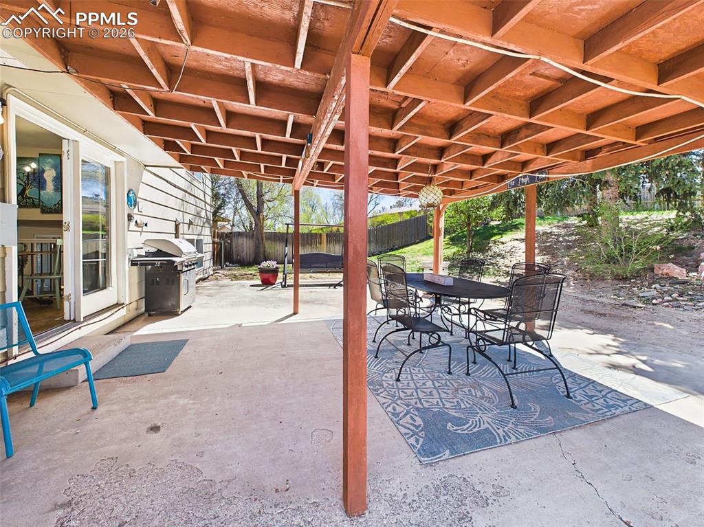Image 40 of 50: Shaded outdoor living area with dining setup and open views of the yard, pe