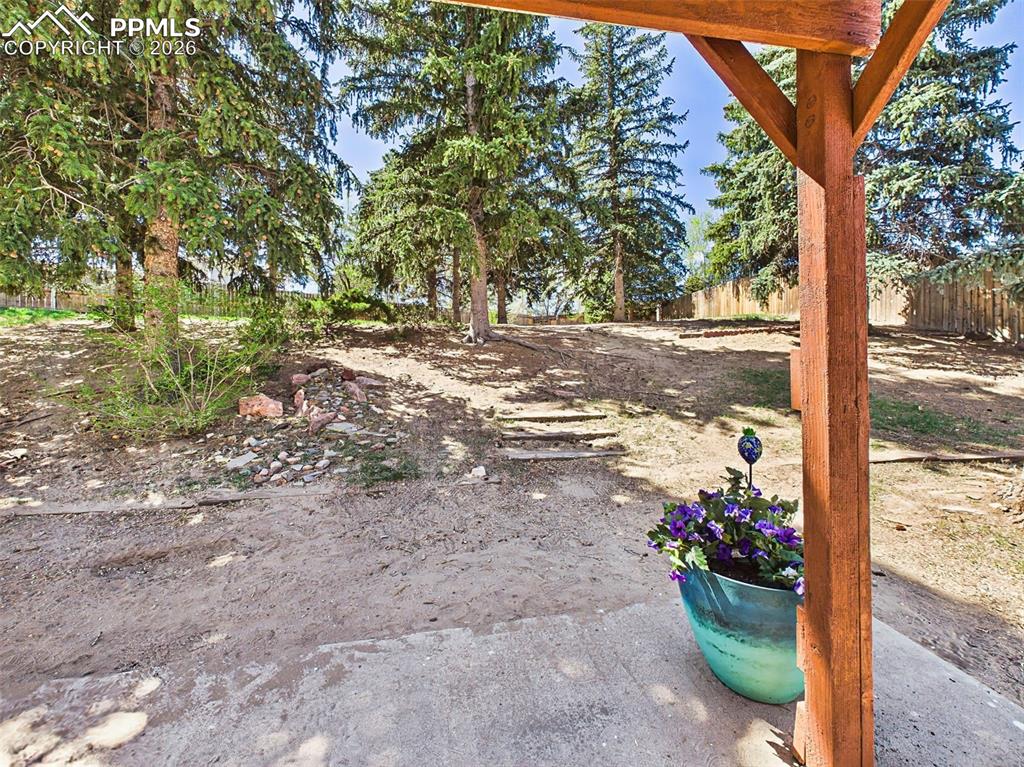 Image 44 of 50: Backyard with gentle slope and mature landscaping, providing depth and char