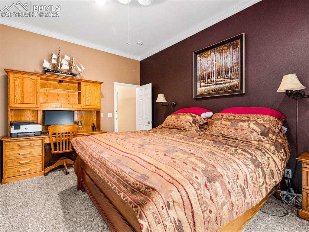Image 16 of 46: Bedroom with ornamental molding, light carpet, and a desk