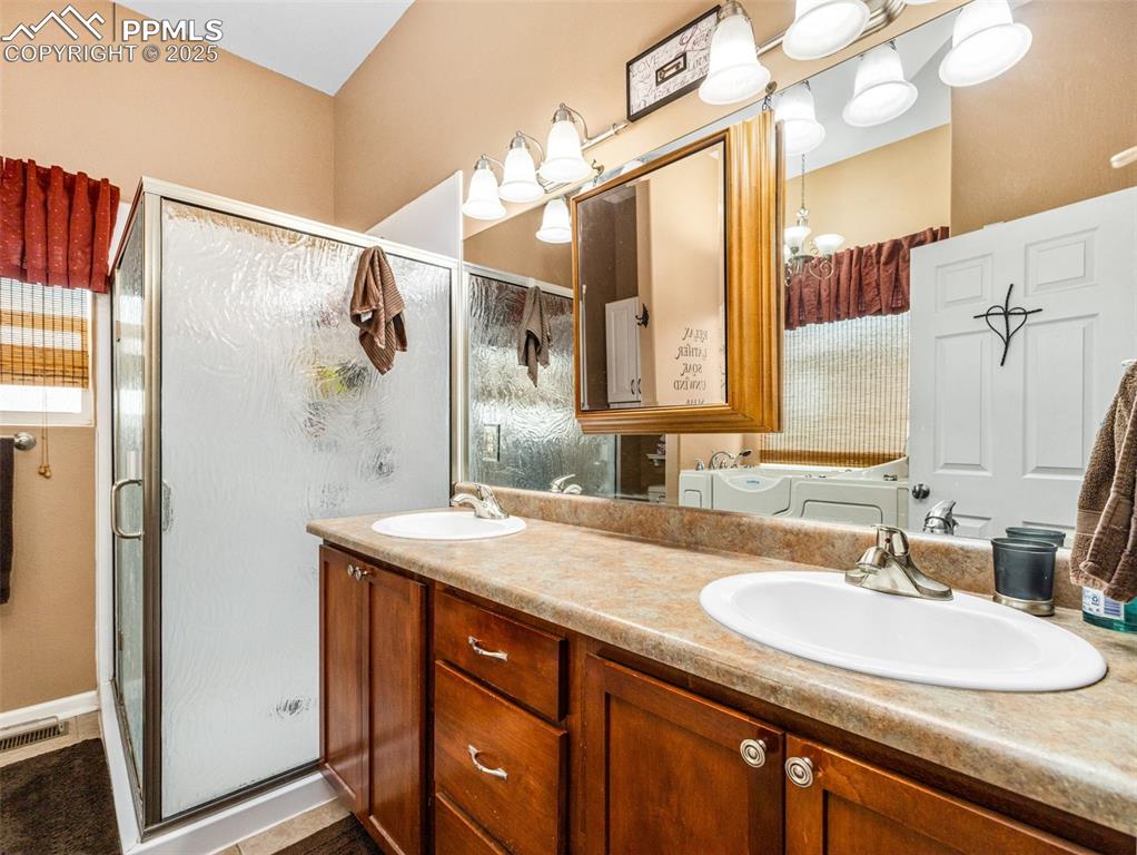 Image 19 of 46: Full bath with a shower stall and double vanity