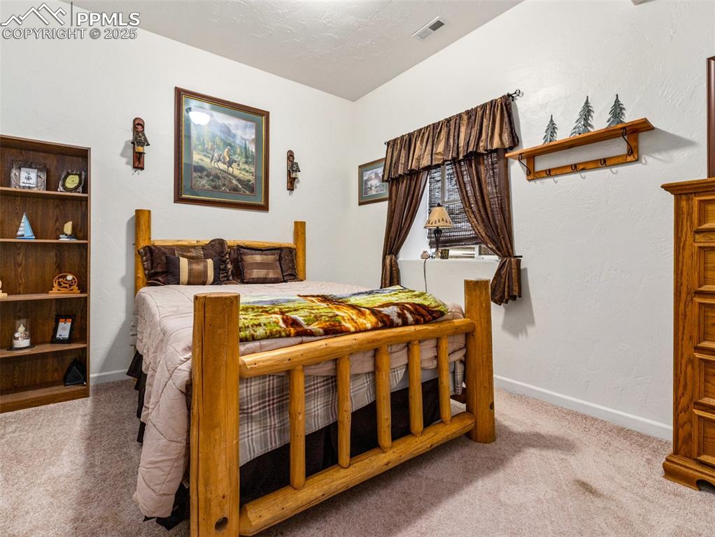 Image 26 of 46: Bedroom with light colored carpet and a textured wall