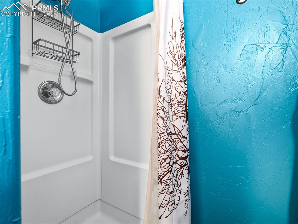 Image 29 of 46: Bathroom featuring a shower with shower curtain and a textured wall