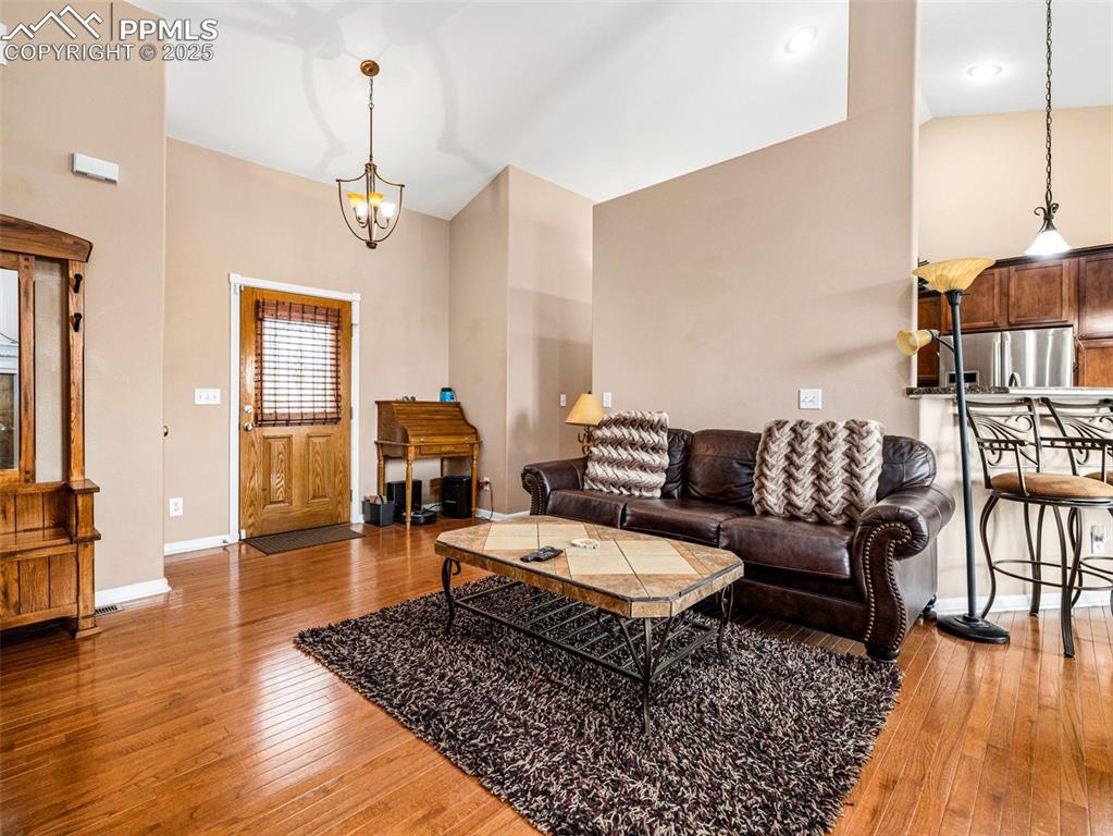 Image 3 of 46: Living room featuring light wood-style flooring, a chandelier, and high vau
