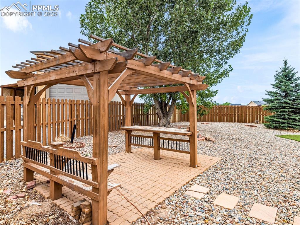 Image 34 of 46: Fenced backyard with a pergola and a patio