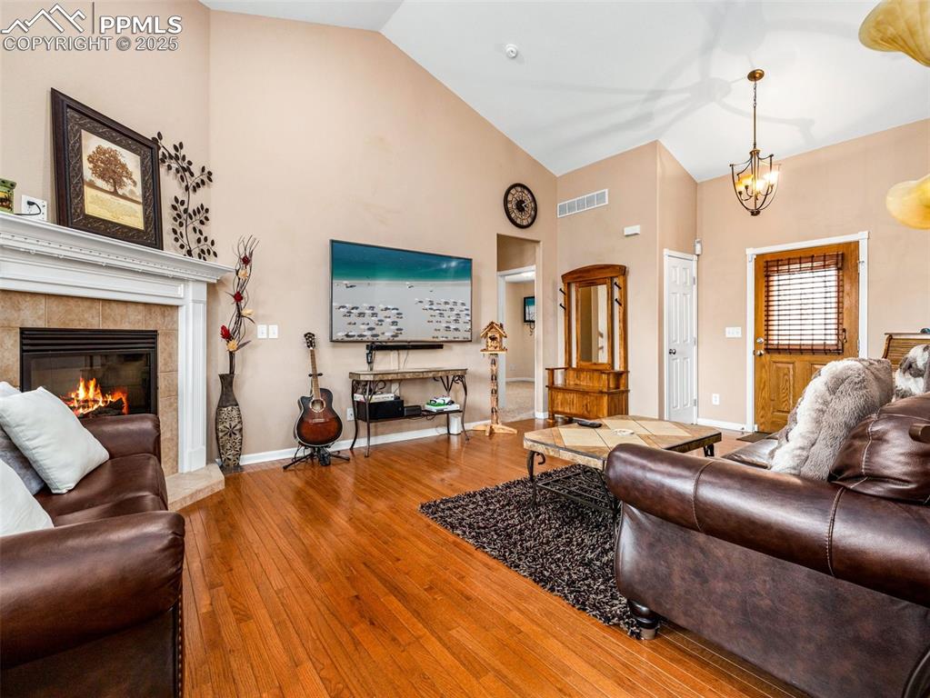 Image 4 of 46: Living room featuring wood-type flooring, high vaulted ceiling, a tiled fir