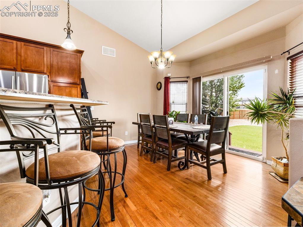 Image 5 of 46: Dining room featuring light wood finished floors, vaulted ceiling, and a ch