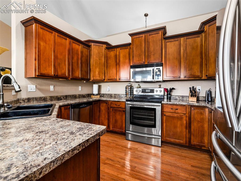 Image 7 of 46: Kitchen featuring appliances with stainless steel finishes, dark wood finis