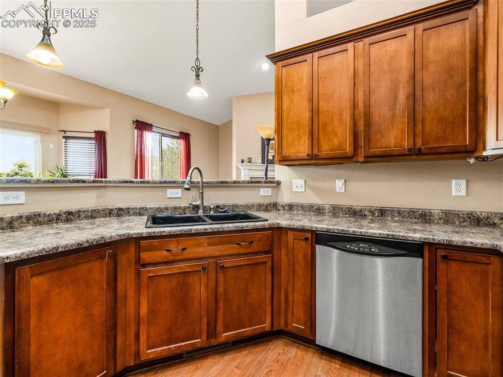 Image 8 of 46: Kitchen with stainless steel dishwasher, pendant lighting, light wood-style