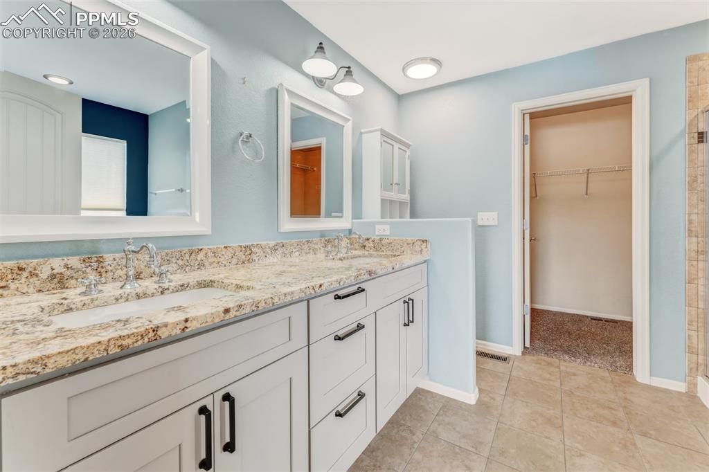 Image 15 of 35: Primary bathroom with dual sinks, granite countertops and large walk-in clo