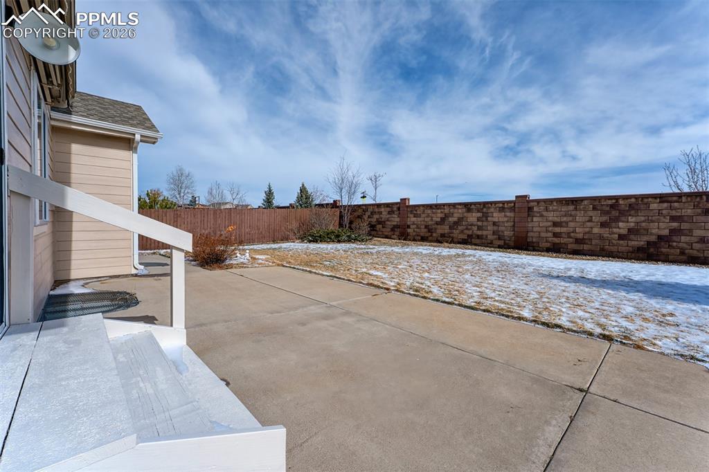 Image 31 of 35: Large concrete patio and nicely landscaped backyard with sprinkler system.