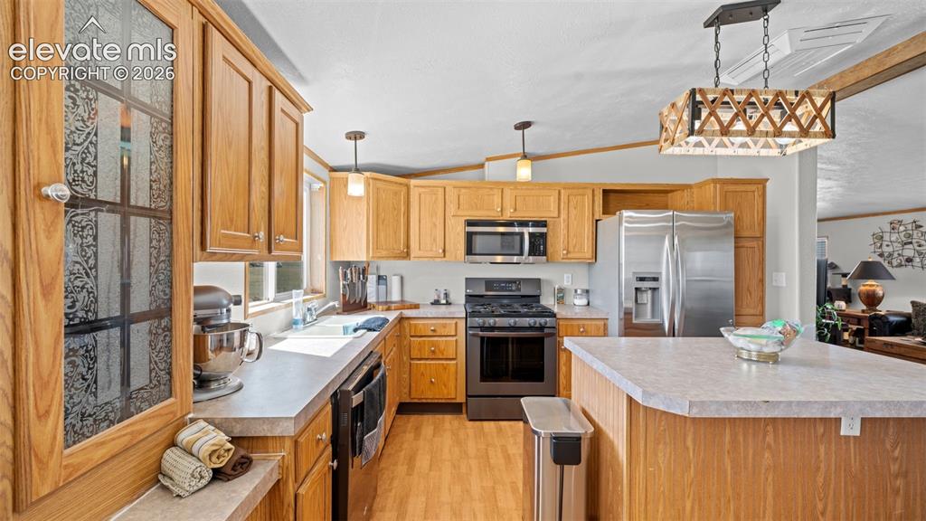 Image 11 of 40: Kitchen featuring wood-finish cabinetry, stainless steel appliances, a cent
