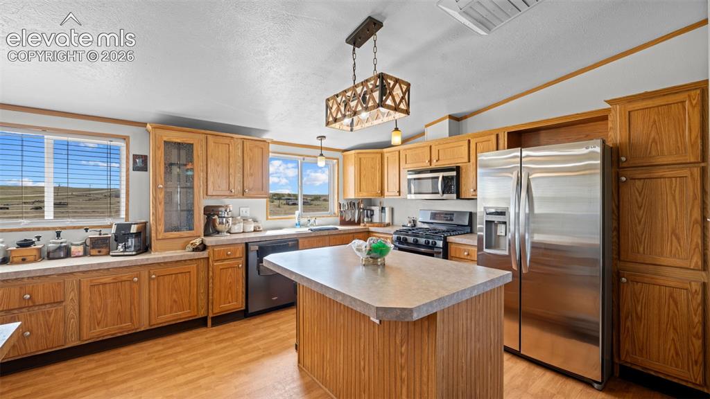 Image 12 of 40: Kitchen featuring wood-finish flooring, wood cabinetry, and a central islan