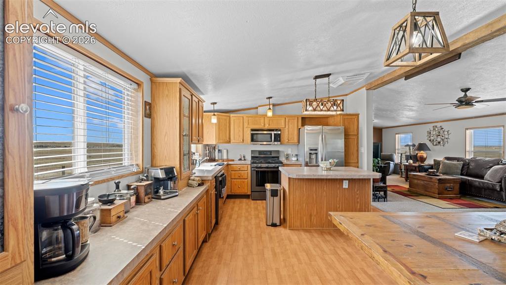 Image 13 of 40: Open-concept kitchen featuring wood-finish cabinetry, stainless steel appli