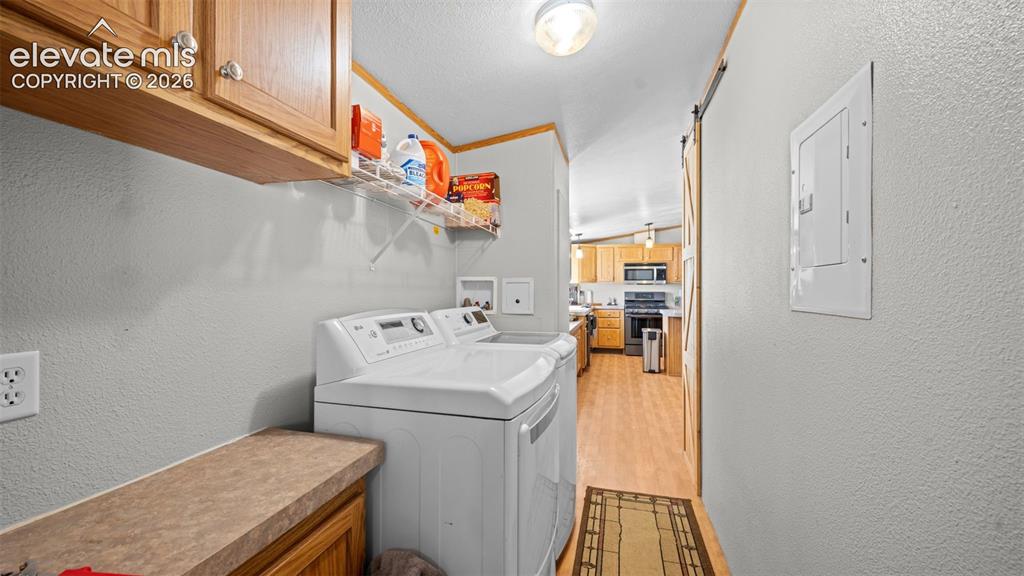 Image 14 of 40: Dedicated laundry area featuring overhead cabinetry, a built-in countertop,