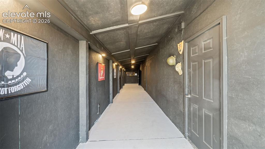 Image 21 of 40: Long hallway with dark textured walls, light-colored flooring, and overhead