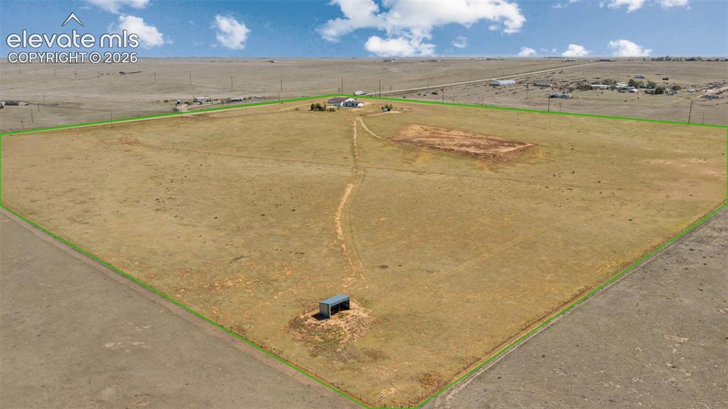 Image 34 of 42: Expansive land parcel with defined boundaries, featuring a single-story dwe