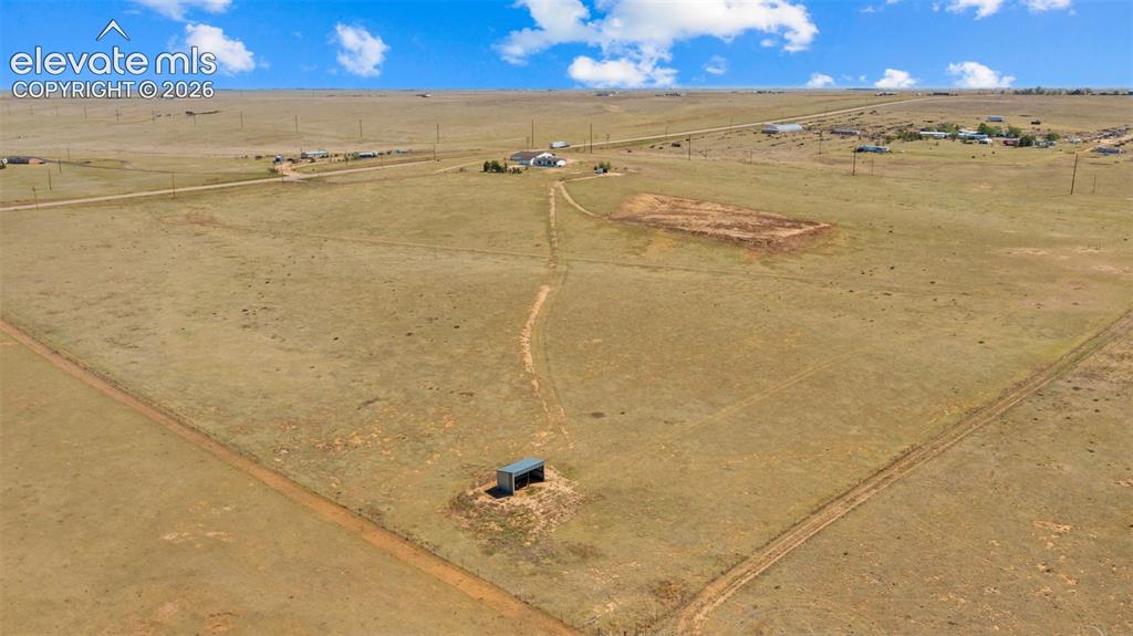 Image 34 of 40: Expansive open land with a small structure and visible dirt trails