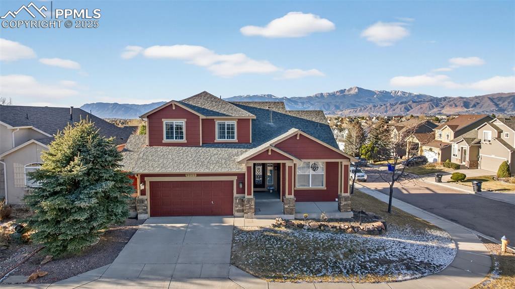 Caption: View of front of house featuring driveway, roof with shingles, and a mountain view