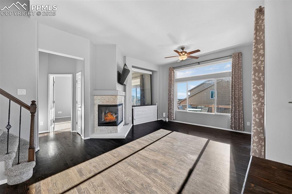 Image 12 of 50: Unfurnished living room with a multi sided fireplace, dark wood-style floor