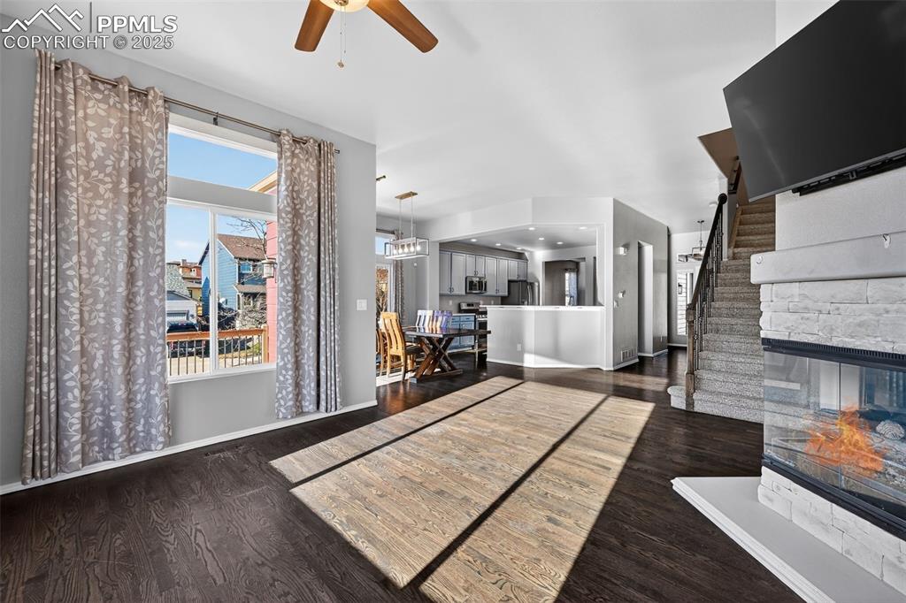 Image 14 of 50: Unfurnished living room with dark wood-type flooring, a fireplace, stairway