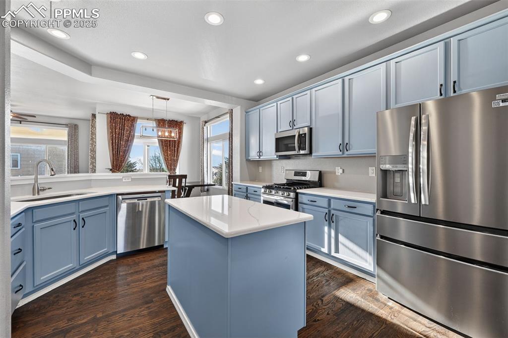 Image 18 of 50: Kitchen with stainless steel appliances, blue cabinets, a center island, de