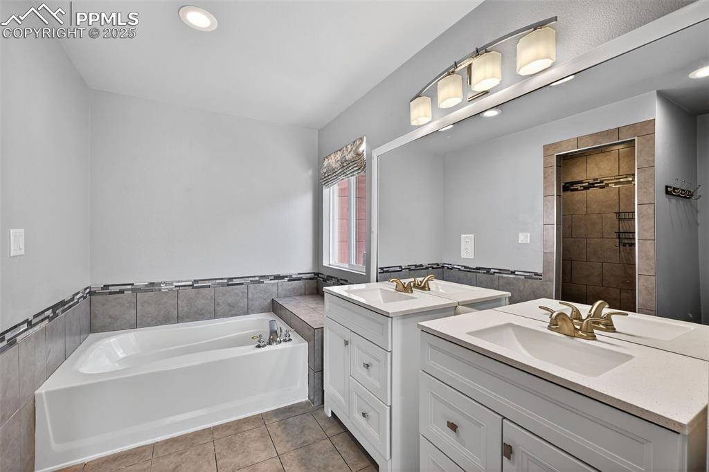 Image 30 of 50: Bathroom featuring two vanities, a garden tub, recessed lighting, tile wall
