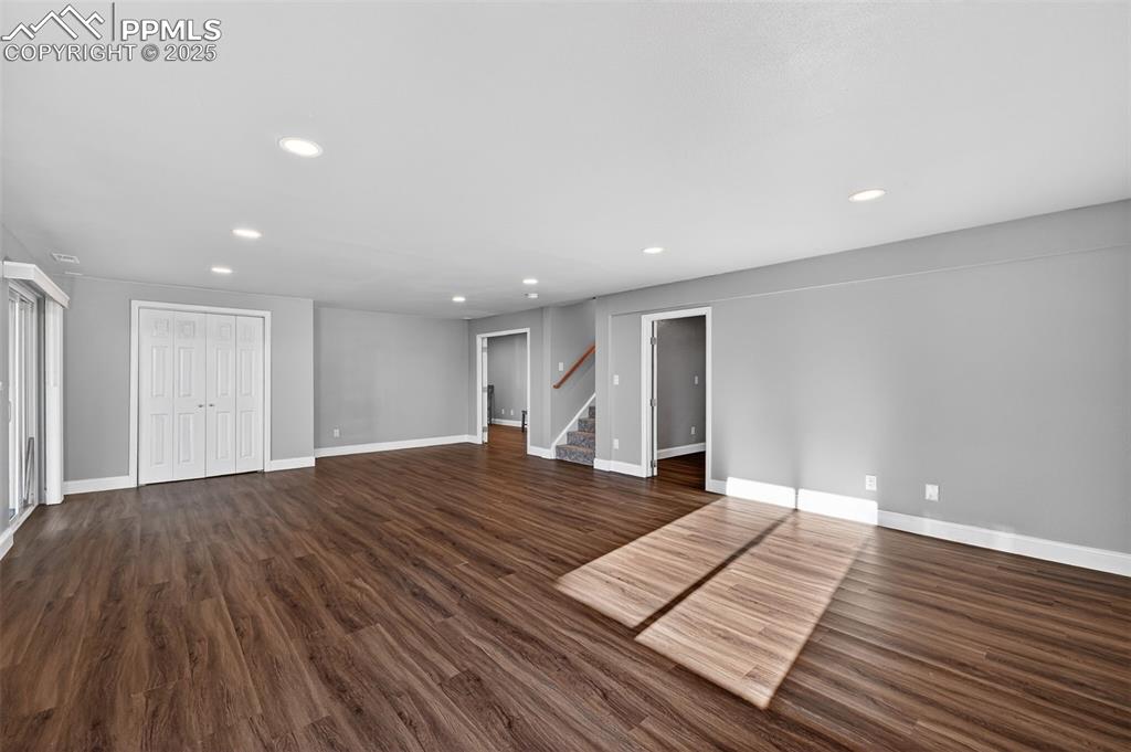 Image 37 of 50: Unfurnished living room with recessed lighting, stairs, and dark wood-type 