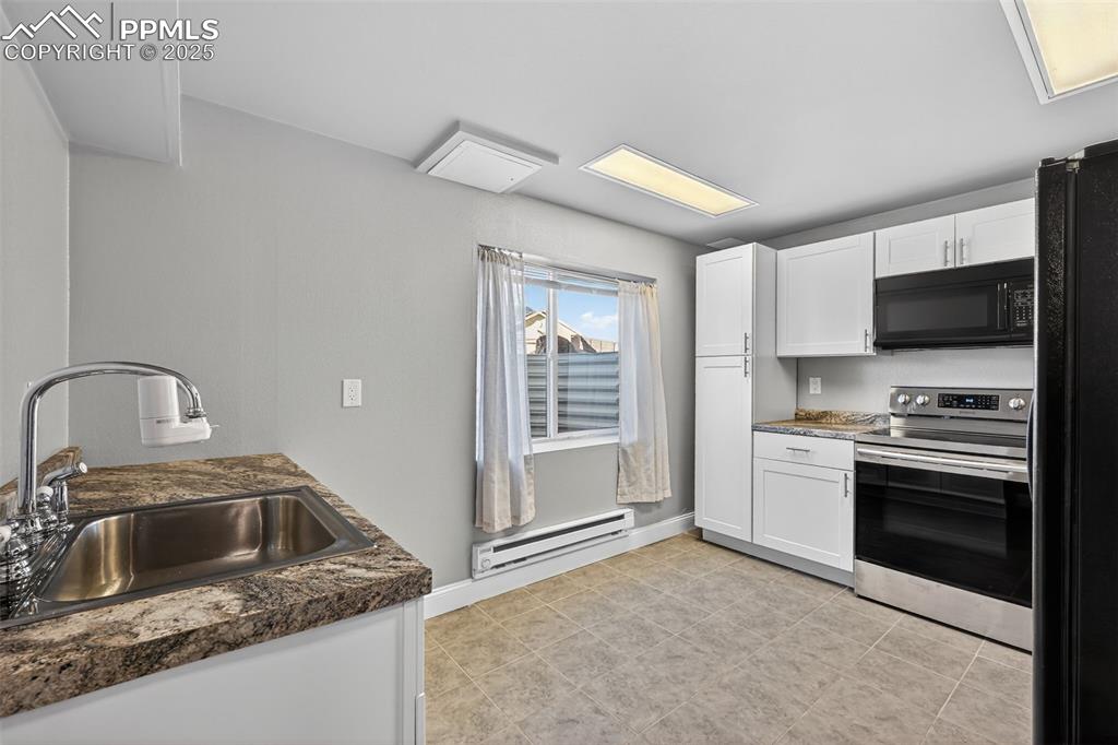 Image 43 of 50: 2nd Kitchen featuring black appliances, white cabinets.