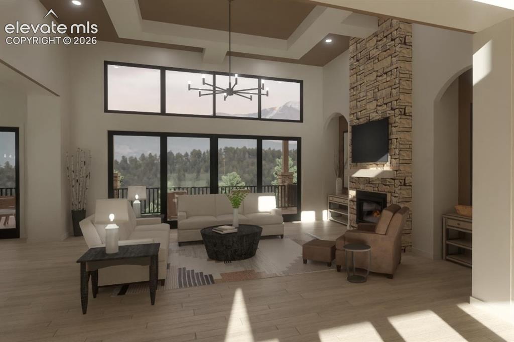 Image 12 of 24: Expansive living space featuring a high vaulted ceiling, stone fireplace, a