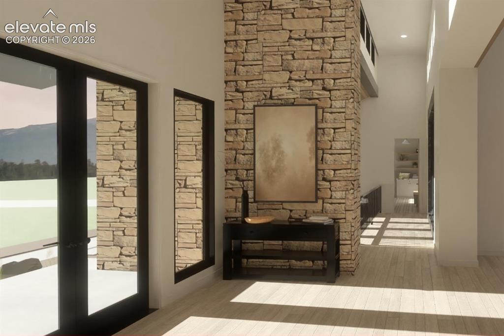 Image 13 of 24: Stone architectural feature with a high ceiling, wood-finish flooring, and