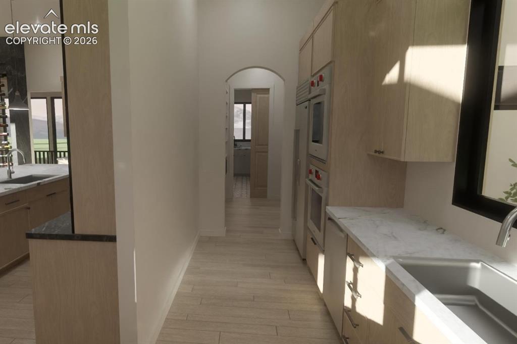 Image 19 of 24: Secondary prep kitchen and separate food pantry with light wood-finish cabi