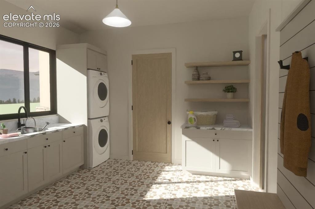Image 23 of 24: Patterned floor tile, stacked laundry appliances, white cabinetry with coun
